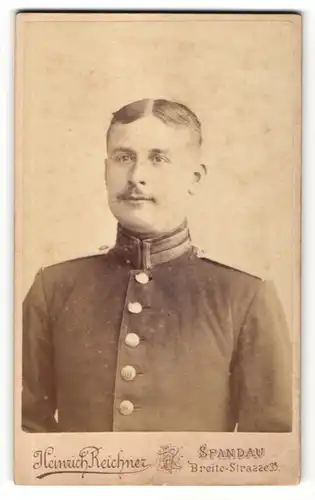Fotografie Heinrich Reichner, Berlin-Spandau, Portrait charmant lächelnder Soldat mit Scheitel und Schnauzer in Uniform
