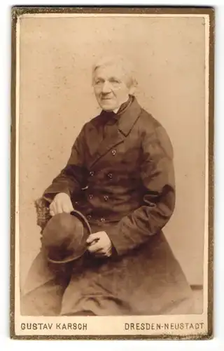 Fotografie Gustav Karsch, Dresden-Neustadt, Portrait charmanter betagter Herr mit grauem Haar und Hut im Mantel
