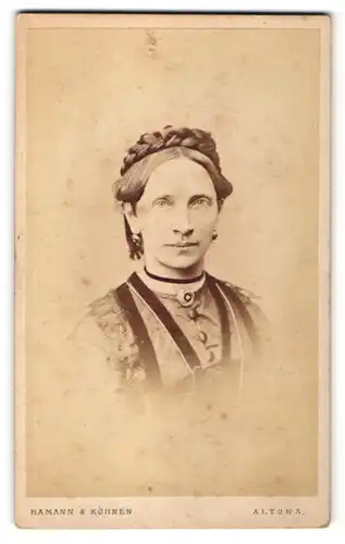 Fotografie Hamann & Köhnen, Hamburg-Altona, Portrait hübsche Dame mit Flechtfrisur, Ohrringen und Brosche