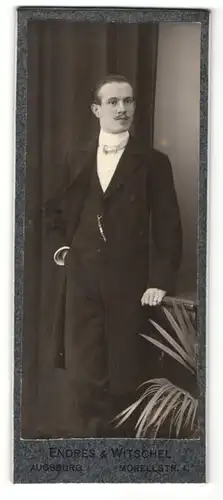 Fotografie Endres & Witschel, Augsburg, Portrait hübscher junger Mann mit Schnauzer im schwarzen Anzug