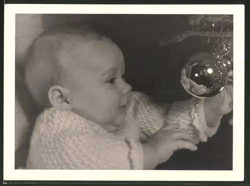 Fotografie Weihnachten, Baby betrachtet Spiegelbild in der Christbaumkugel