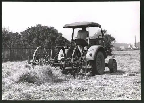 Fotografie Traktor, Landwirt steuert Schlepper über einen mit Heu bedeckten Acker