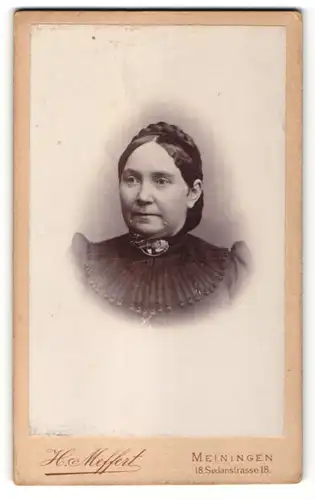 Fotografie H. Meffert, Meiningen, Portrait dunkelhaarige Frau mit Flechtfrisur und Brosche am Kragen