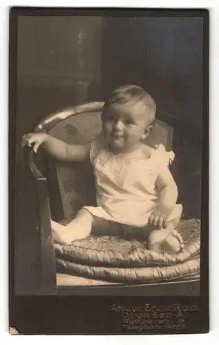 Fotografie Atelier Ernst Rost, Dresden-A., Portrait Kleinkind im weissen Hemd auf einem Stuhl