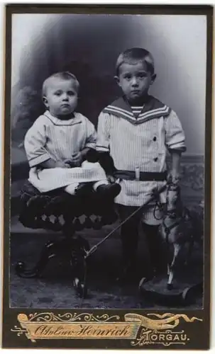 Fotografie Franz Heinrich, Torgau, Portrait Junge in Matrosenuniform und Mädchen auf einem Stuhl