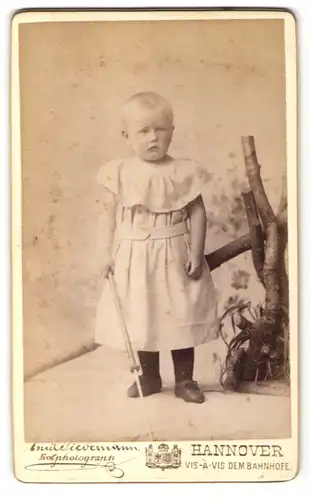 Fotografie Emile Tiedemann, Hannover, Portrait Kleinkind mit geschorenem Haar in Kleidchen