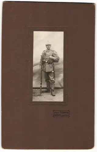 Fotografie Atelier Neumann, Zwickau, Kriegsausmarsch, Soldat in Feldgrau mit Gewehr & Pickelhaubenüberzug Rgt. 133