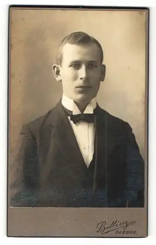 Fotografie Bolling, Örebro, Portrait hübscher junger Mann im schwarzen Anzug und schwarzer Fliege