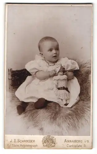 Fotografie J. S. Schroeder, Annaberg i/S, Portrait Säugling mit Puppe