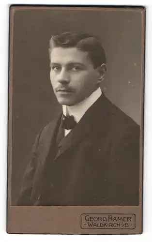 Fotografie Georg Ramer, Waldkirch i / B., Portrait junger Mann mit Seitenscheitel und Fliege im Anzug