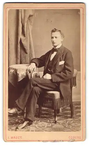 Fotografie S. Mauer, Coburg, Portrait Junger Mann im Anzug sitzt an einem Tisch