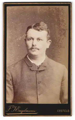Fotografie F. J. Engelmann, Crefeld, Portrait junger Mann mit Oberlippenbart im karierten Jackett