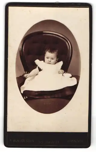 Fotografie F. Wunder Sohn, Hannover, Portrait Kleinkind im Kleidchen auf einem Sessel sitzend
