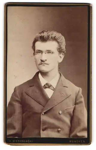 Fotografie V. Bieganowski, München, Portrait junger Herr mit zurückgekämmtem Haar und Brille