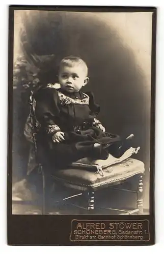 Fotografie Alfred Stöwer, Schöneberg, Portrait kleines Mädchen im eleganten Kleid auf Stuhl sitzend