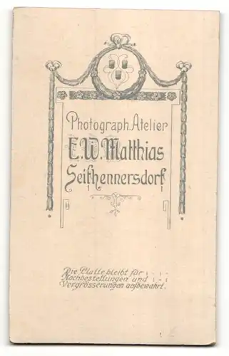 Fotografie E. W. Matthias, Seifhennersdorf, Portrait Junge mit Buch im Anzug an einem Tisch lehnend