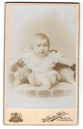 Fotografie Wilhelm Stein, Berlin, Portrait Kleinkind im weissen Hemdchen auf Sessel sitzend