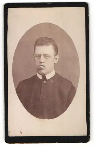 Fotografie unbekannter Fotograf und Ort, Portrait junger Mann mit Brille in einer Robe