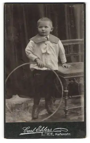 Fotografie Carl Ehlers, Lehe, Portrait kleiner Junge im Matrosenanzug mit Reifen an Hocker gelehnt