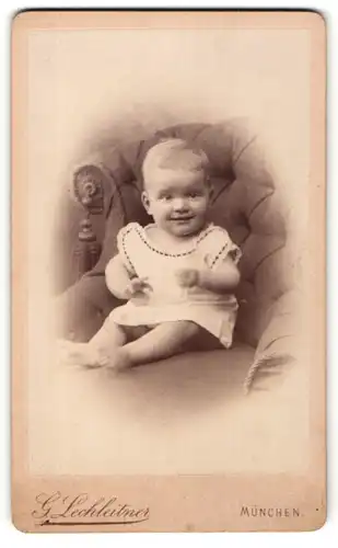 Fotografie G. Lechleitner, München, Portrait niedliches Baby im weissen Hemd auf Sessel sitzend