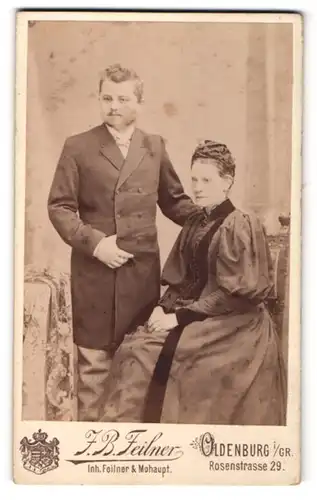 Fotografie J. B. Feilner, Oldenburg i / Gr., Portrait ältere bürgerliche Dame mit Haube auf Stuhl sitzend und Herr