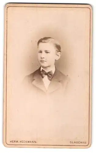 Fotografie Herm. Heckmann, Glauchau, Portrait kleiner Junge mit Seitenscheitel u. Fliege im Anzug