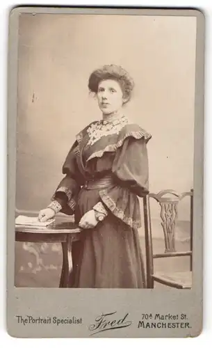 Fotografie Fred, Manchester, Portrait lächelnde Dame in elegantem Kleid an Tisch gelehnt