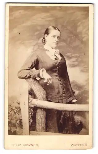 Fotografie Fred Downer, Watford, Portrait junge Dame in zeitgenössischer Kleidung an einem Zaun lehnend