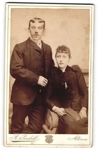 Fotografie Rudolf Przibill, Altona, Mann mit Mittelscheitel und Frau mit Buch im Schoss