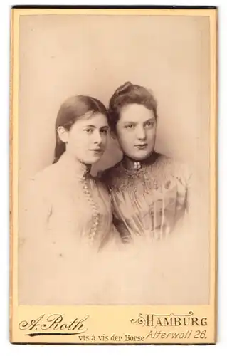 Fotografie A. Roth, Hamburg, Portrait zwei junge hübsche Damen mit zeitgenössischen Frisuren in eleganten Kleidern