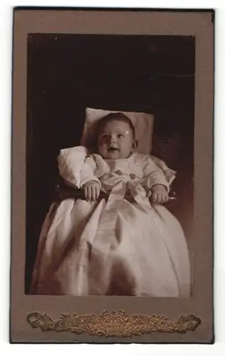 Fotografie unbekannter Fotograf und Ort, Portrait Säugling in feierlicher Kleidung