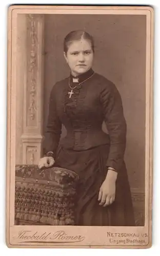 Fotografie Theobald Römer, Netzschkau i / S., Portrait junge Dame mit Kreuzkette im eleganten Kleid auf Lehne gestützt
