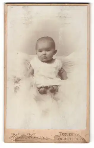 Fotografie Herm. Krausse, Treuen i / V., Lengenfeld i / V., Portrait niedliches Baby im weissen Hemd auf Fell sitzend