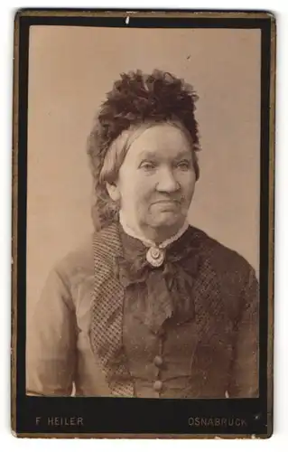 Fotografie F. Heiler, Osnabrück, Portrait ältere lächelnde Dame mit Haube u. Kragenbrosche in zeitgenöss. Kleidung