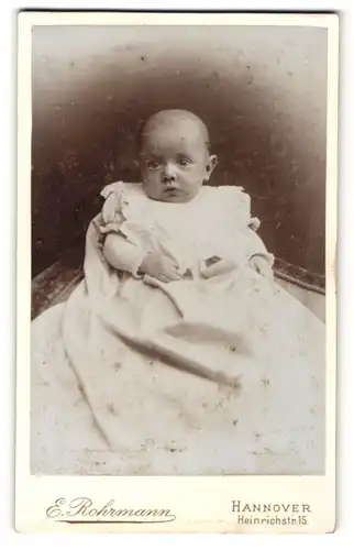 Fotografie E. Rohrmann, Hannover, Portrait niedliches Baby im weissen Kleid auf Stuhl sitzend