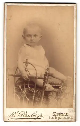 Fotografie H. Strube jr., Zittau, Portrait niedliches Kleinkind im weissen Hemd auf Hocker sitzend
