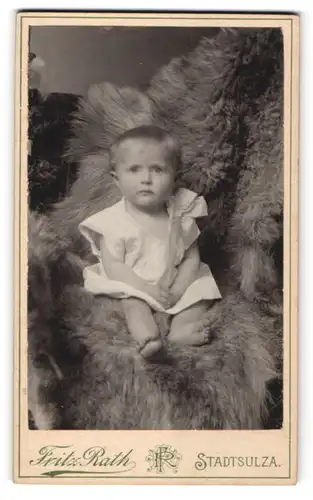 Fotografie Fritz Rath, Stadtsulza, Portrait niedliches Kleinkind im weissen Hemd auf Fell sitzend