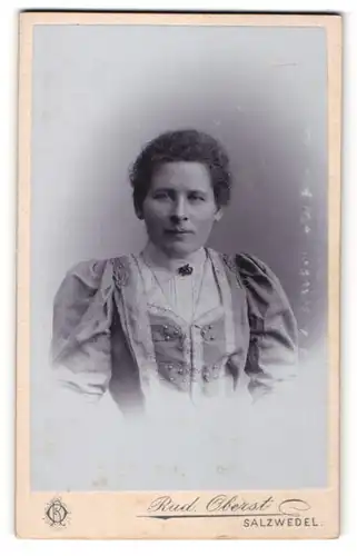 Fotografie Rud. Oberst, Salzwedel, Portrait lächelnde Dame mit zurückgebundenem Haar in modischem Kleid