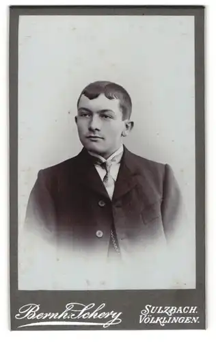 Fotografie Bernh. Schery, Sulzbach, Völklingen, Portrait junger Herr mit zeitgenöss. Frisur u. Krawatte im Anzug