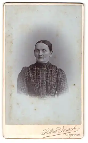 Fotografie Julius Grusche, Neugersdorf, Portrait ältere Dame mit zurückgebundenem Haar im karierten Kleid