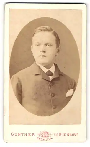 Fotografie Günther, Bruxelles, Portrait junger Herr mit Seitenscheitel u. Fliege im Anzug