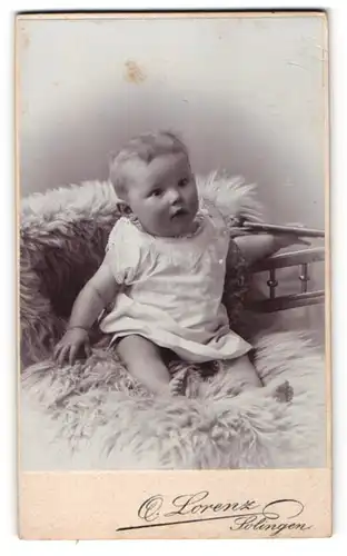 Fotografie Otto Lorenz, Solingen, Portrait niedliches Baby im weissen Hemd auf Fell sitzend