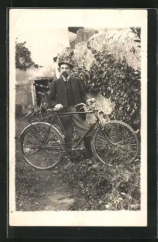 Foto-AK Mann mit seinem Fahrrad an einer Gartenmauer