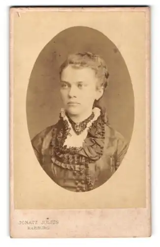 Fotografie Ignatz Julius, Hamburg, Portrait junge Dame mit zurückgebundenem Haar u. Kragenbrosche im eleganten Kleid