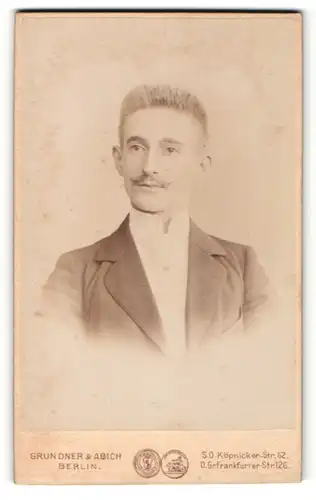 Fotografie Grundner & Abich, Berlin, Portrait junger Herr mit Zwirbelbart u. Krawatte im Anzug