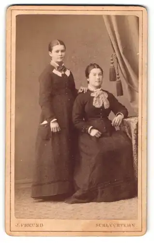 Fotografie J. Freund, Schlüchtern, Portrait bürgerliche Dame mit zurückgebundenem Haar am Tisch sitzend u. andere Dame