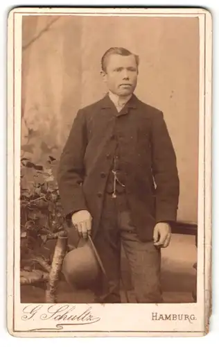 Fotografie G. Schultz, Hamburg, Mann in Dreiteiler mit Melone in der Hand haltend