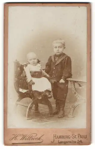Fotografie H. Wittrock, Hamburg-St. Pauli, Portrait niedliches Baby im weissen Kleid auf Stuhl sitzend u. Bruder