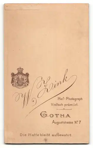Fotografie W. Zink, Gotha, Portrait niedliches Baby im weissen Hemd auf Fell sitzend