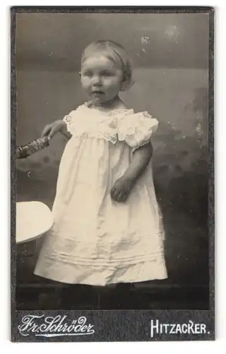 Fotografie Fr. Schröder, Hitzacker, kleines Mädchen in Rüschenkleid mit Spielzeug in Hand
